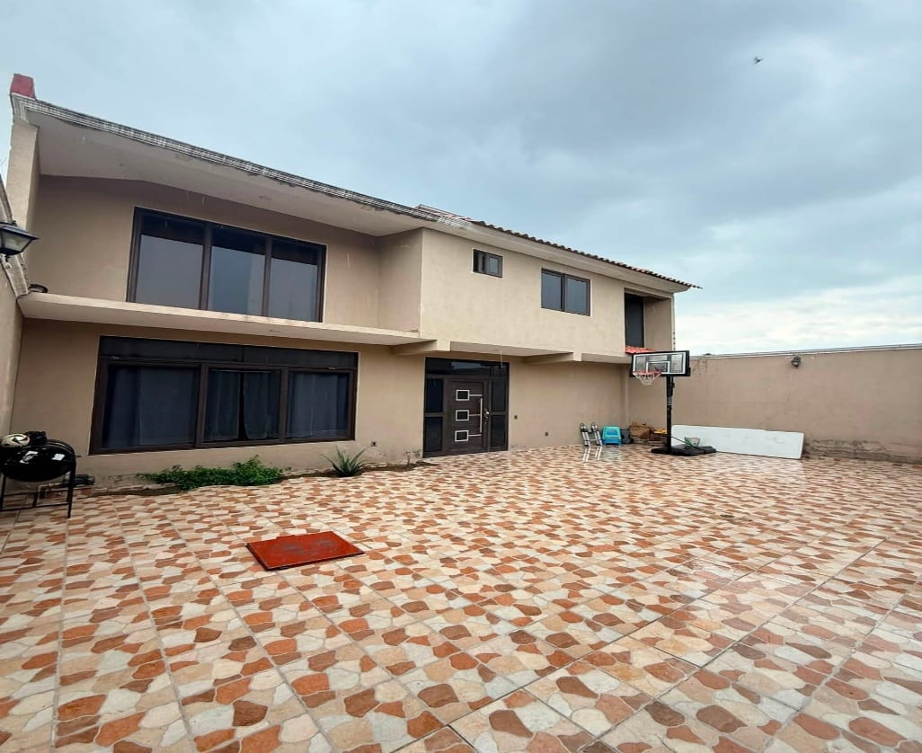 Fachada de la casa con patio amplio y estacionamiento al frente