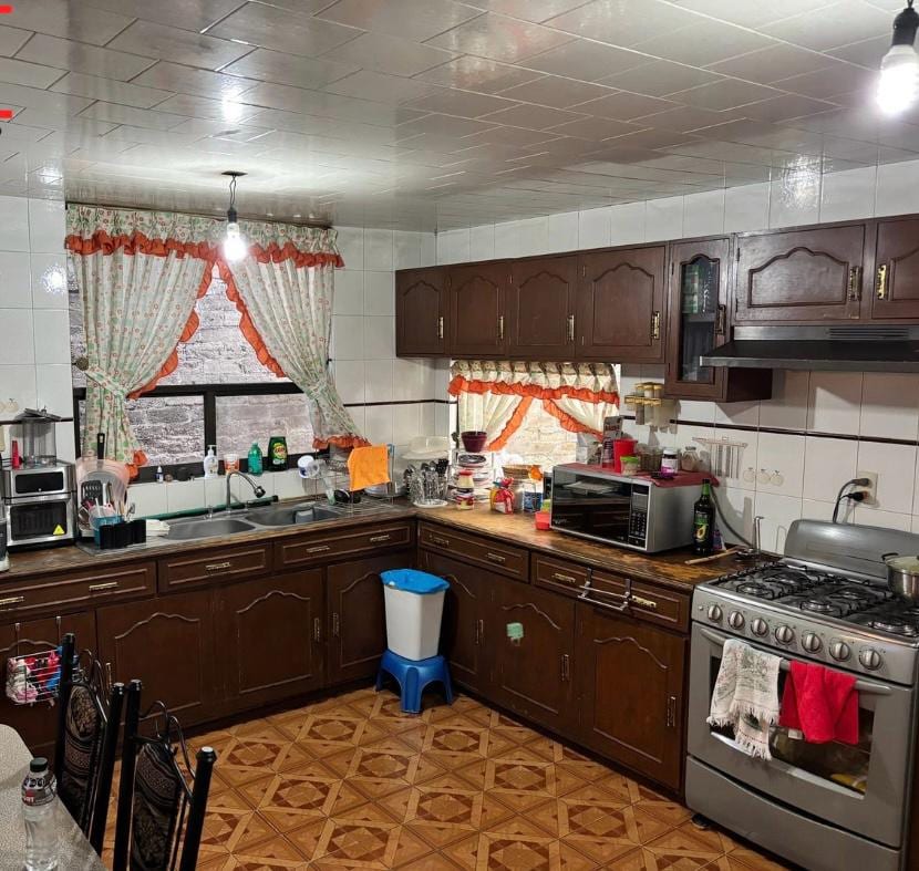 Cocina con muebles de madera y barra en escuadra
