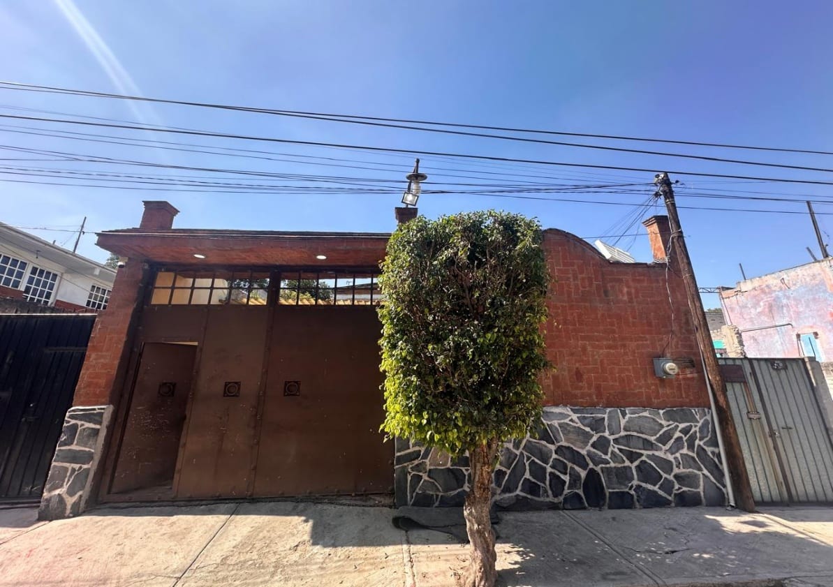 Fachada de la casa con portón de acceso y muro de piedra