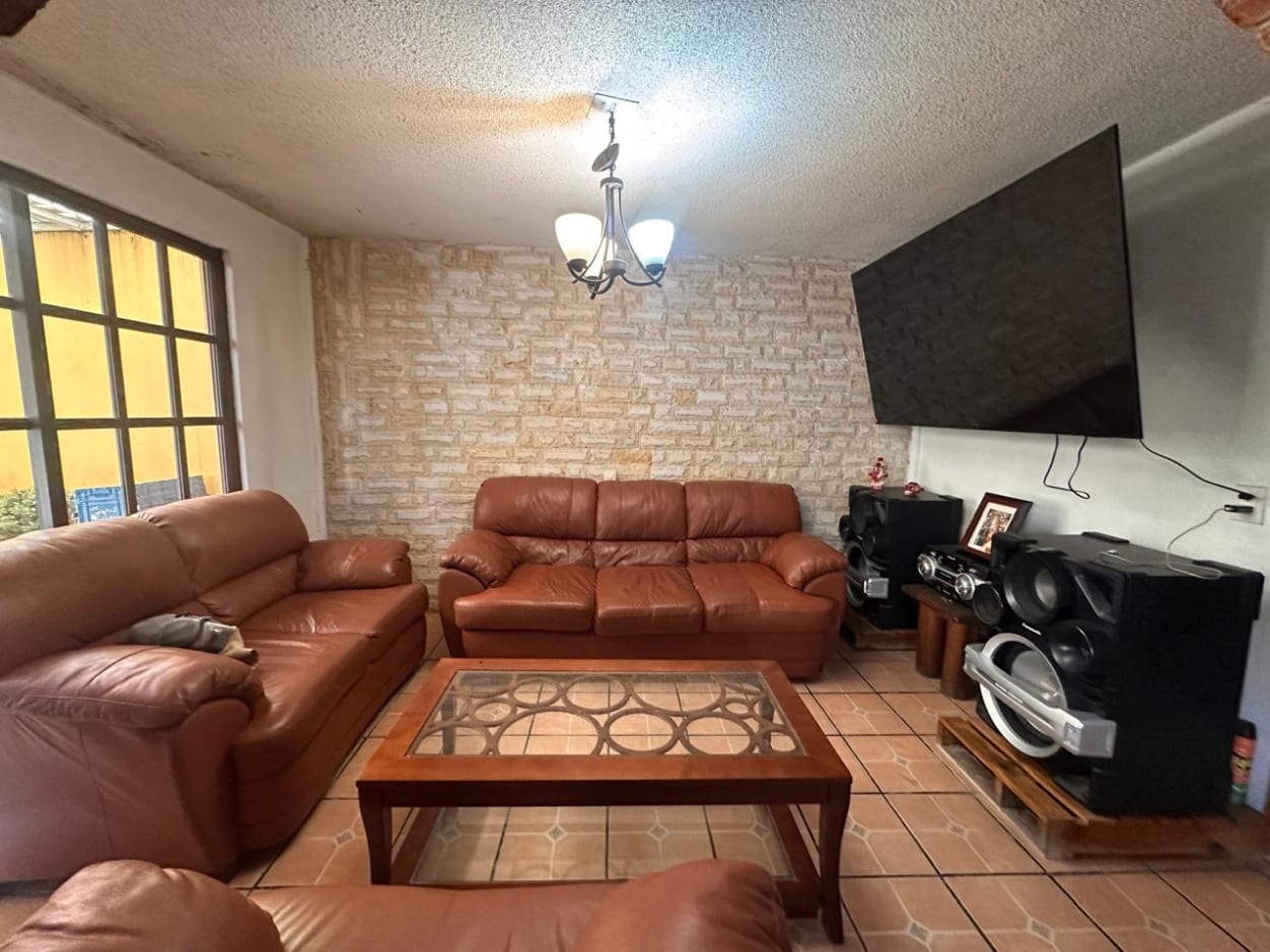 Estancia con muro de ladrillo aparente y ventanal al jardín