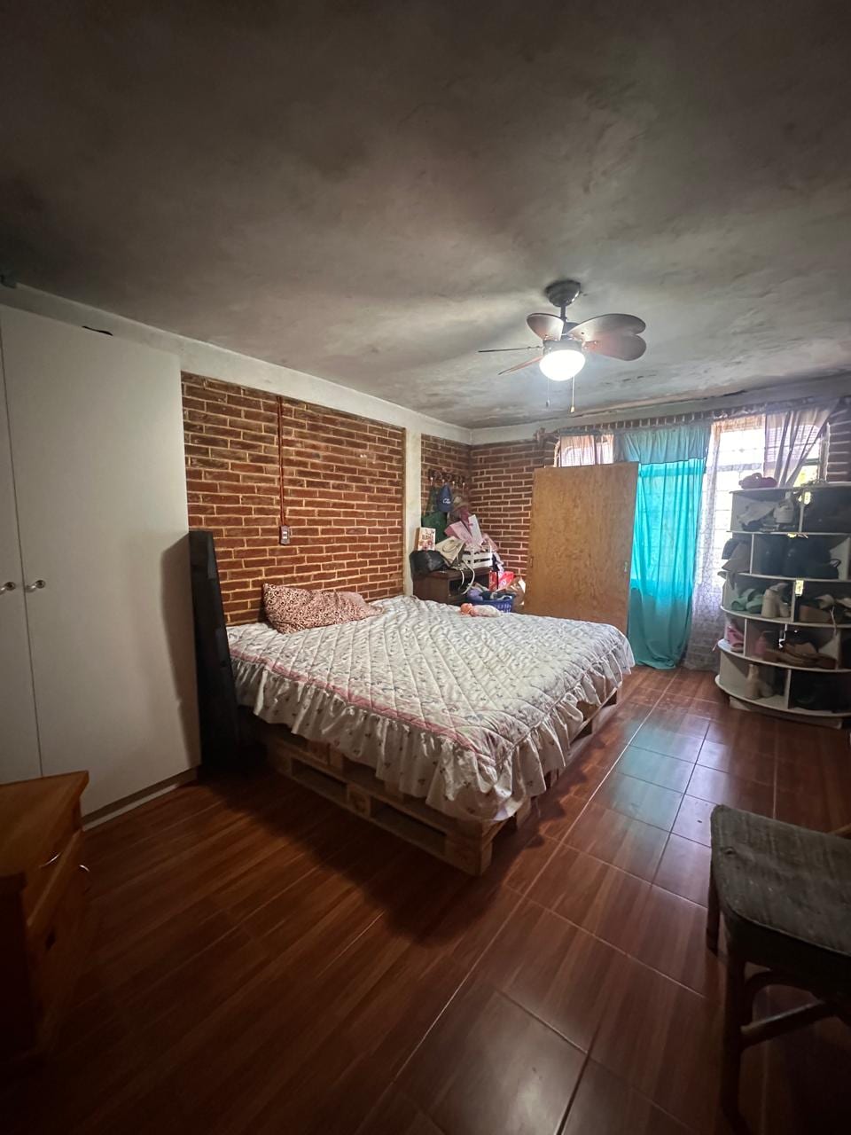 Recámara principal con muro de ladrillo aparente y ventilador de techo