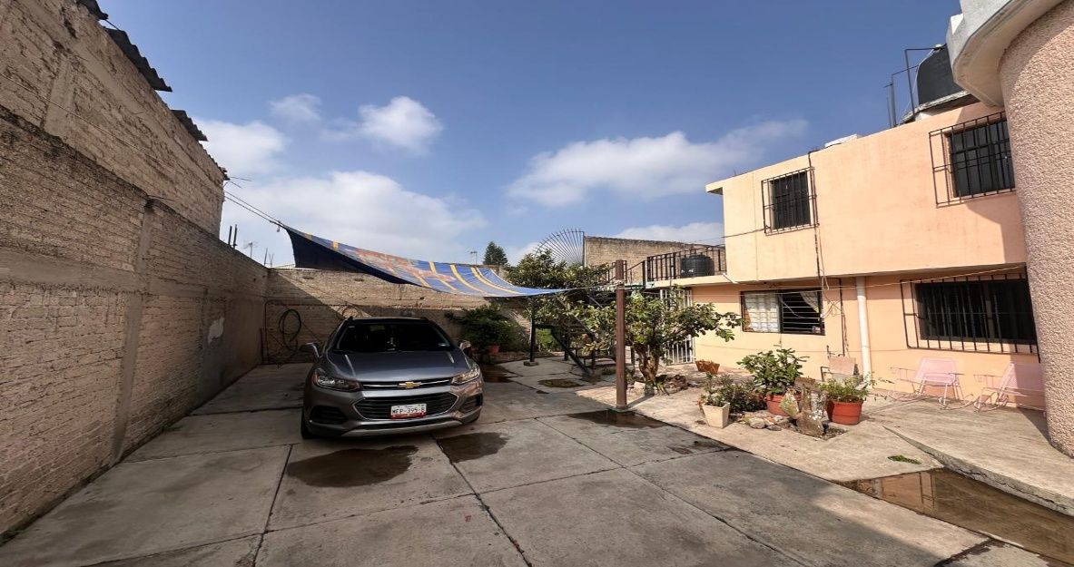 Patio frontal de la casa con espacio de estacionamiento para varios autos