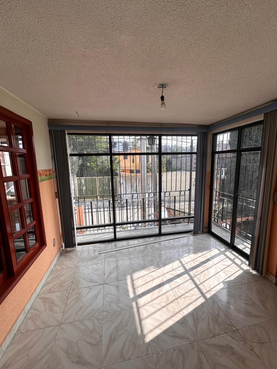 Sala de TV en planta alta con ventanales de piso a techo hacia la terraza