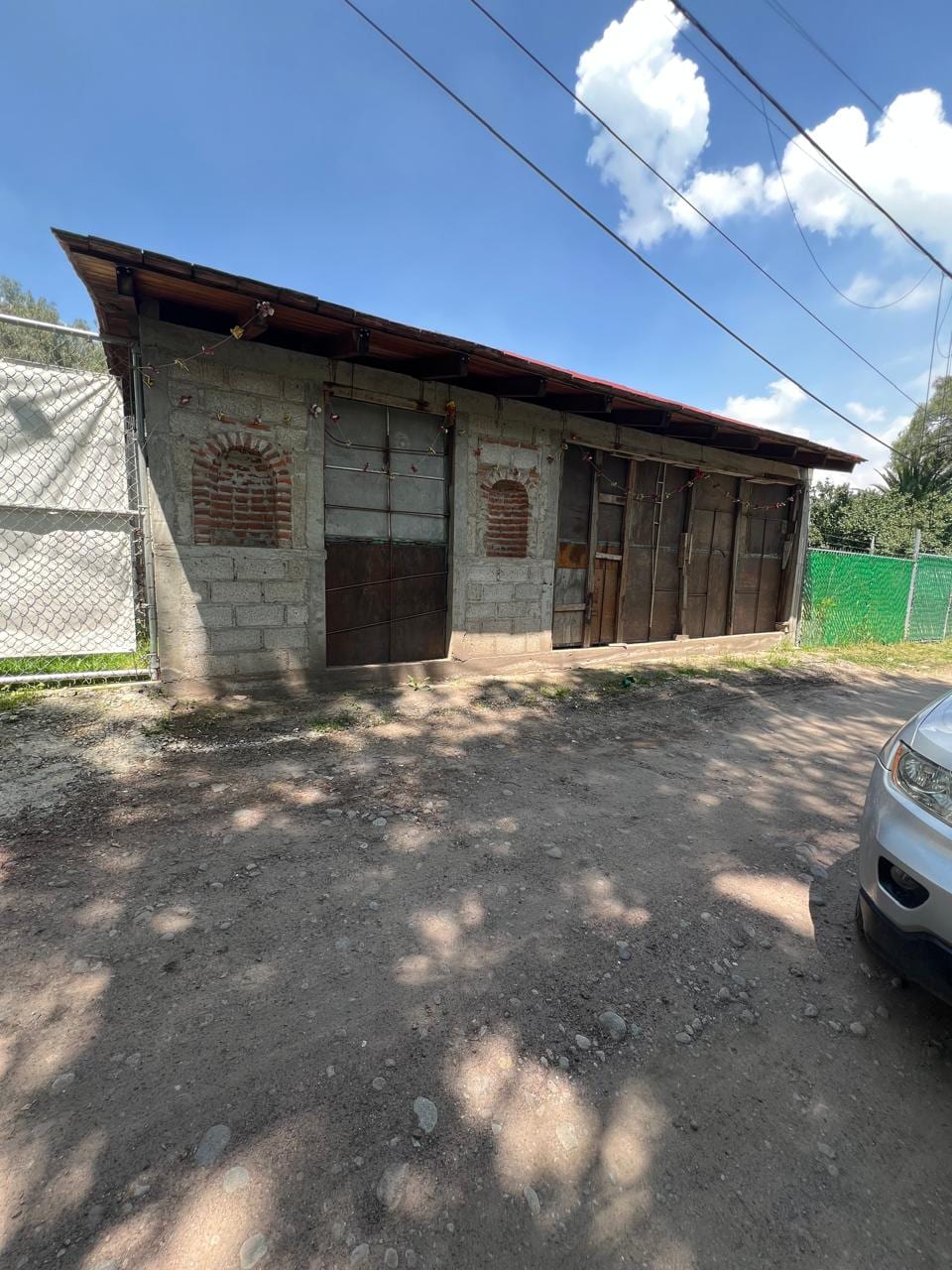 Fachada de la casa en obra gris con muros de block y techumbre de madera
