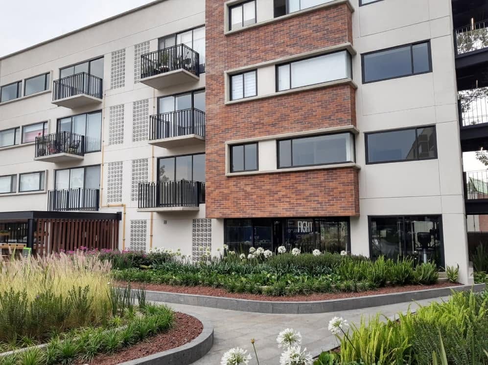 Fachada del conjunto residencial en ladrillo y concreto, con balcones y jardineras al frente