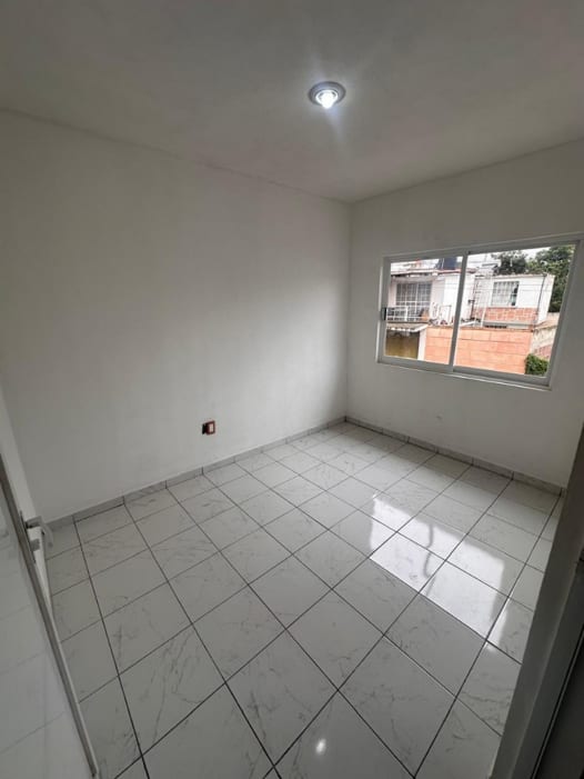 Recámara con ventana al exterior y piso de loseta tipo mármol