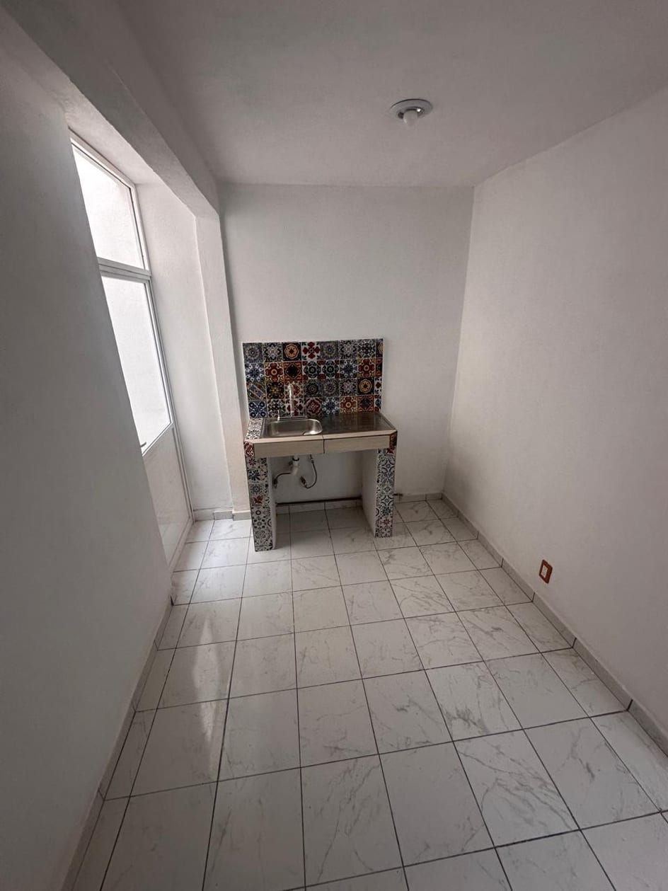 Cocina con tarja de acero y respaldo de azulejo tipo talavera, junto a la ventana