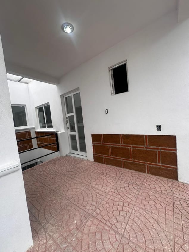 Acceso al departamento con terraza de piso rojo y zócalo de ladrillo