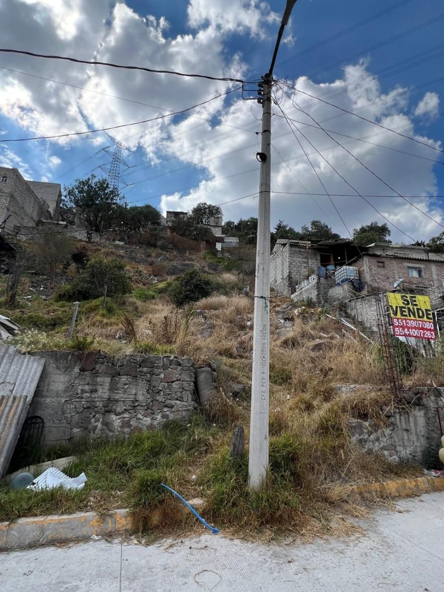 Acceso al terreno desde la calle, con banqueta y postería