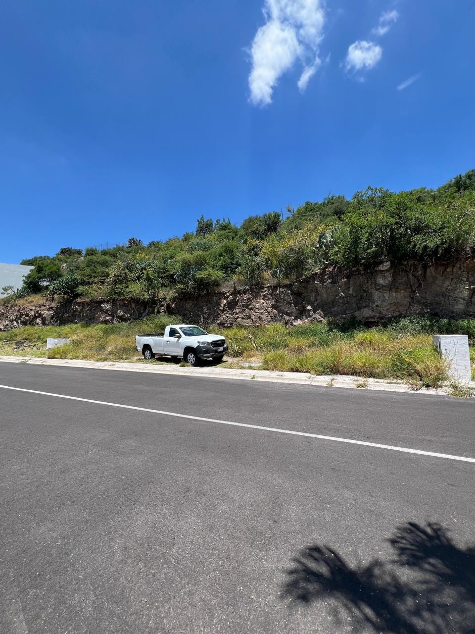 Frente del terreno visto desde la calle, con el talud de roca y las mojoneras en los extremos